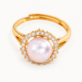 A gold-tone ring with a pale pink pearl-like centre surrounded by clear stones — studio view | Jeweliano
