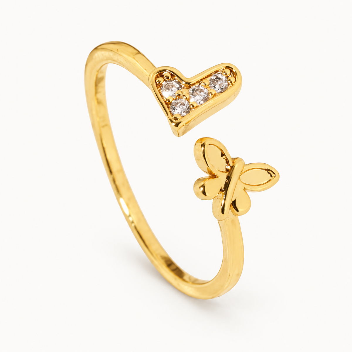 An open gold-tone ring combining a stone-set heart and a butterfly-inspired detail — studio view | Jeweliano