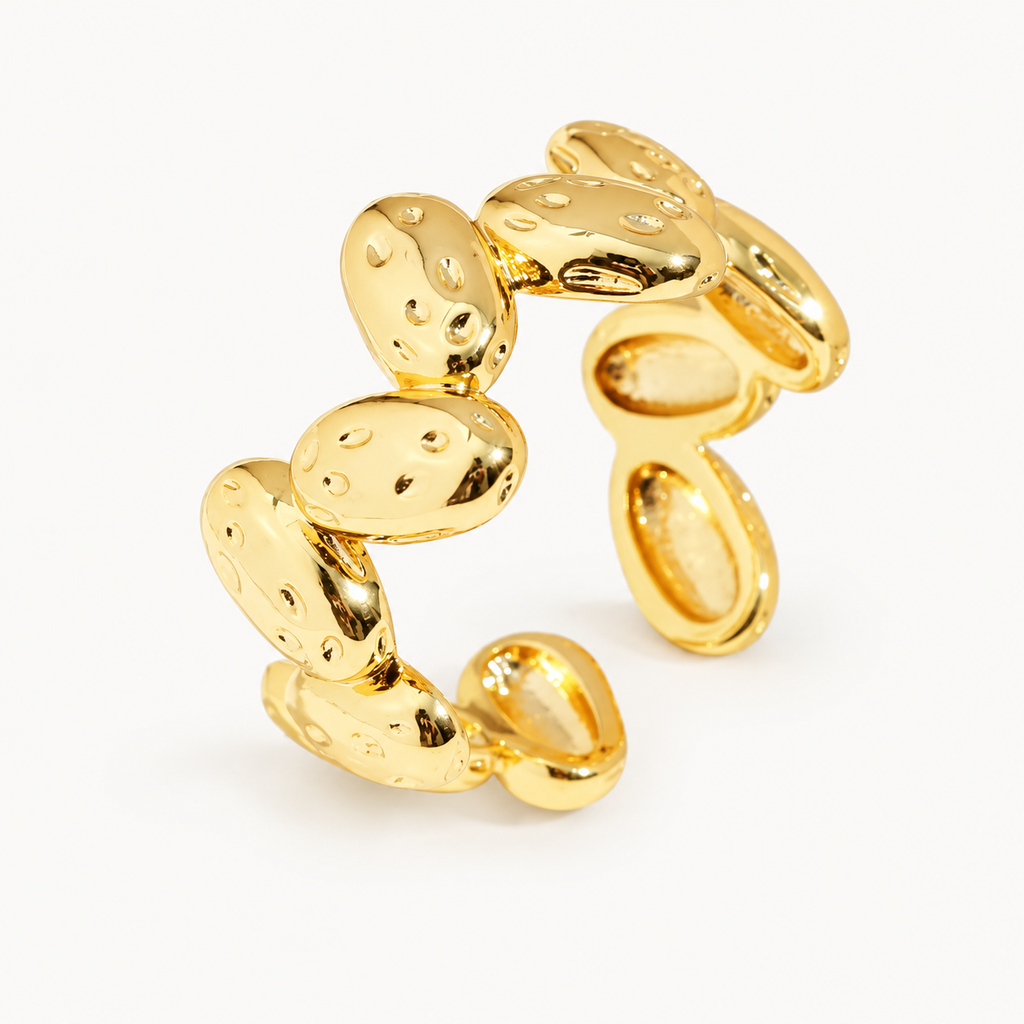 An open gold-tone ring with a sequence of rounded, textured disc details — studio view | Jeweliano