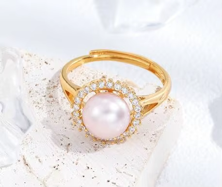A gold-tone ring with a pale pink pearl-like centre surrounded by clear stones — alternate view | Jeweliano